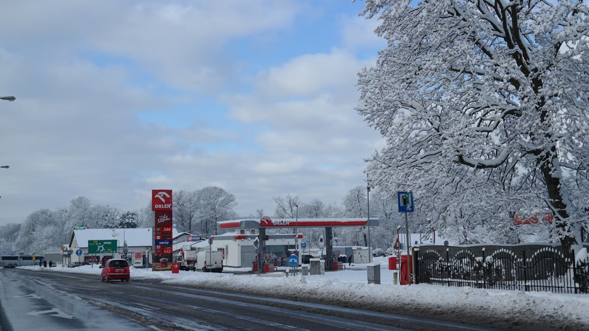 A snow-covered Orlen gas station on a winter's day with clear skies.